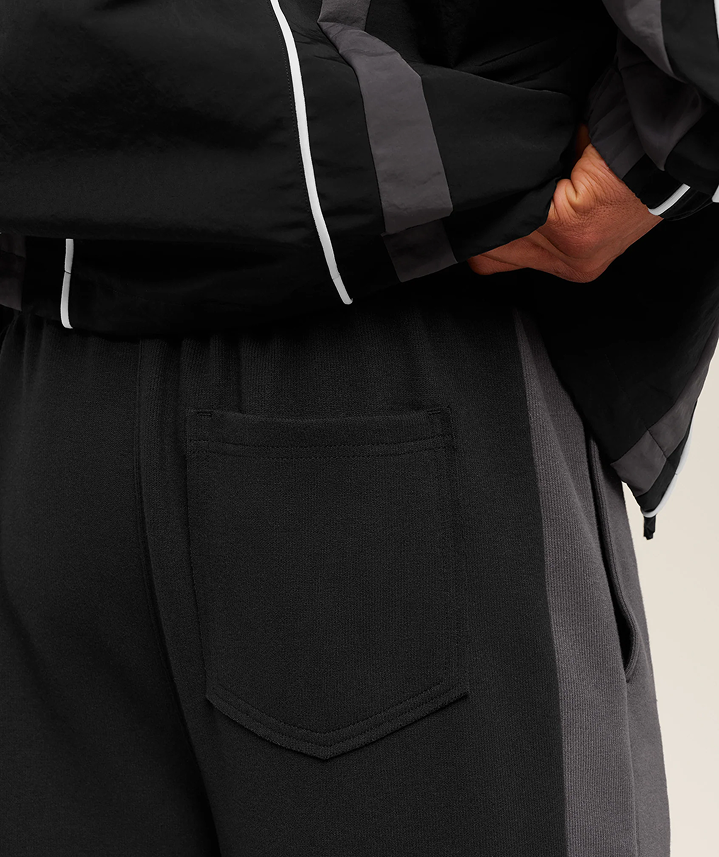 Person wearing a black outfit with gray accents on a beige background